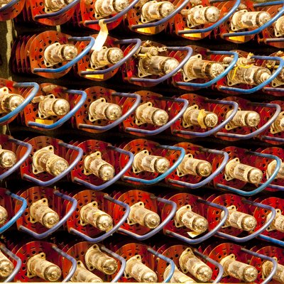 Bildfüllend: rote Elektroröhren mit goldfarbenen Metallkappen und blauen Bügeln