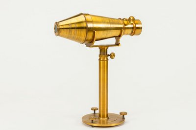 Der Metalltubus dieser Nachbildung der Daguerrotypie-Kamera mit Voigtländeroptik ruht horizontal auf einem Stativ. Sie ist aus poliertem Messing gefertigt.