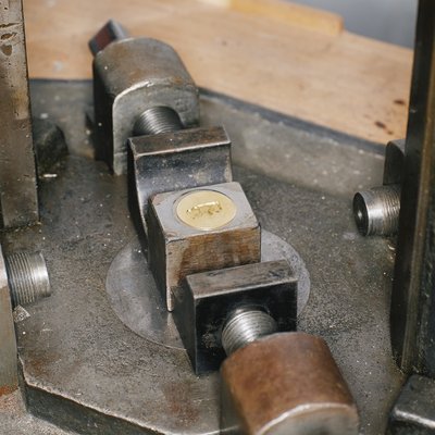 Eine Metallmütze nach der Prägung, sie liegt noch in der Prägemaschine.