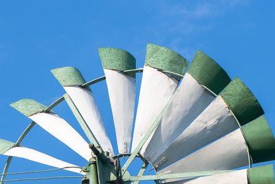 Die obere Hälfte eines Windrads mit grünen Spitzen vor blauem Himmel