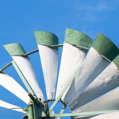 Die obere Hälfte eines Windrads mit grünen Spitzen vor blauem Himmel