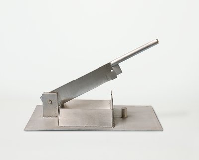 Der Stierhodenschneider wurde um 1950 von der Firma Schering gebaut. Es handelt sich um eine besonders stabile Schlagmesserklinge, die auf eine Metallplatte montiert ist, und mit einem Metallgriff an der Seite heruntergedrückt wird.
