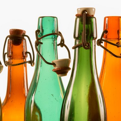 Die Flaschenhälse der historischen Bierflaschen aus braunem und grünem Glas glänzen im Gegenlicht. Ihre Bügelverschlüsse sind teilweise geöffnet.