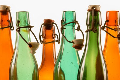 Die Flaschenhälse der historischen Bierflaschen aus braunem und grünem Glas glänzen im Gegenlicht. Ihre Bügelverschlüsse sind teilweise geöffnet.
