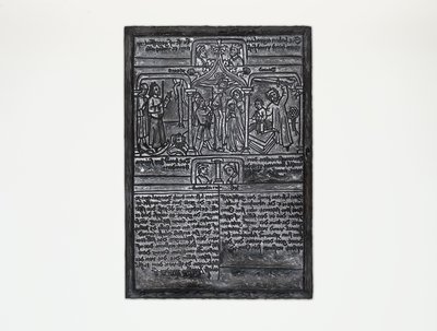 Der hölzerne Druckstock einer Armenbibel zeigt in der oberen Hälfte religiöse Motive. Im Zentrum ist Jesus am Kreuz, in der unteren Hälfte steht Text.