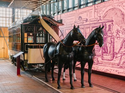 Eine Straßenbahn, die von zwei Pferdeattrappen gezogen wird.