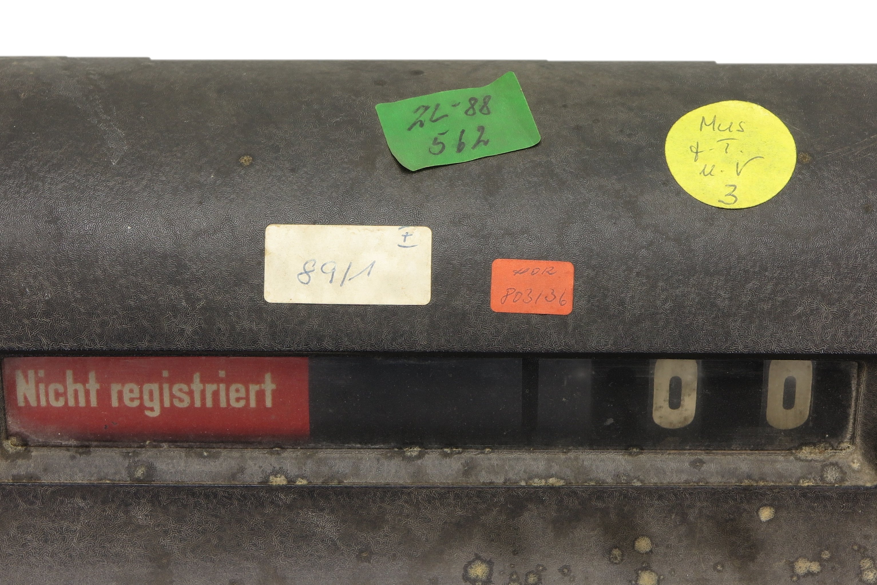 Oberer Teil einer Registrierkasse aus den 1930er Jahren mit vier farbigen Aufklebern der KuA. Die Aufkleber tragen Zahlen und Buchstaben.