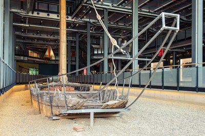 Der Kaffenkahn ist ein hölzernes Schiff, dessen Bodenplanken bis zur Wasserlinie aufgebogen sind. Am aus Metall nachgebauten Heck des schlanken Kahns sind das Ruder und die Pinne zu erkennen.