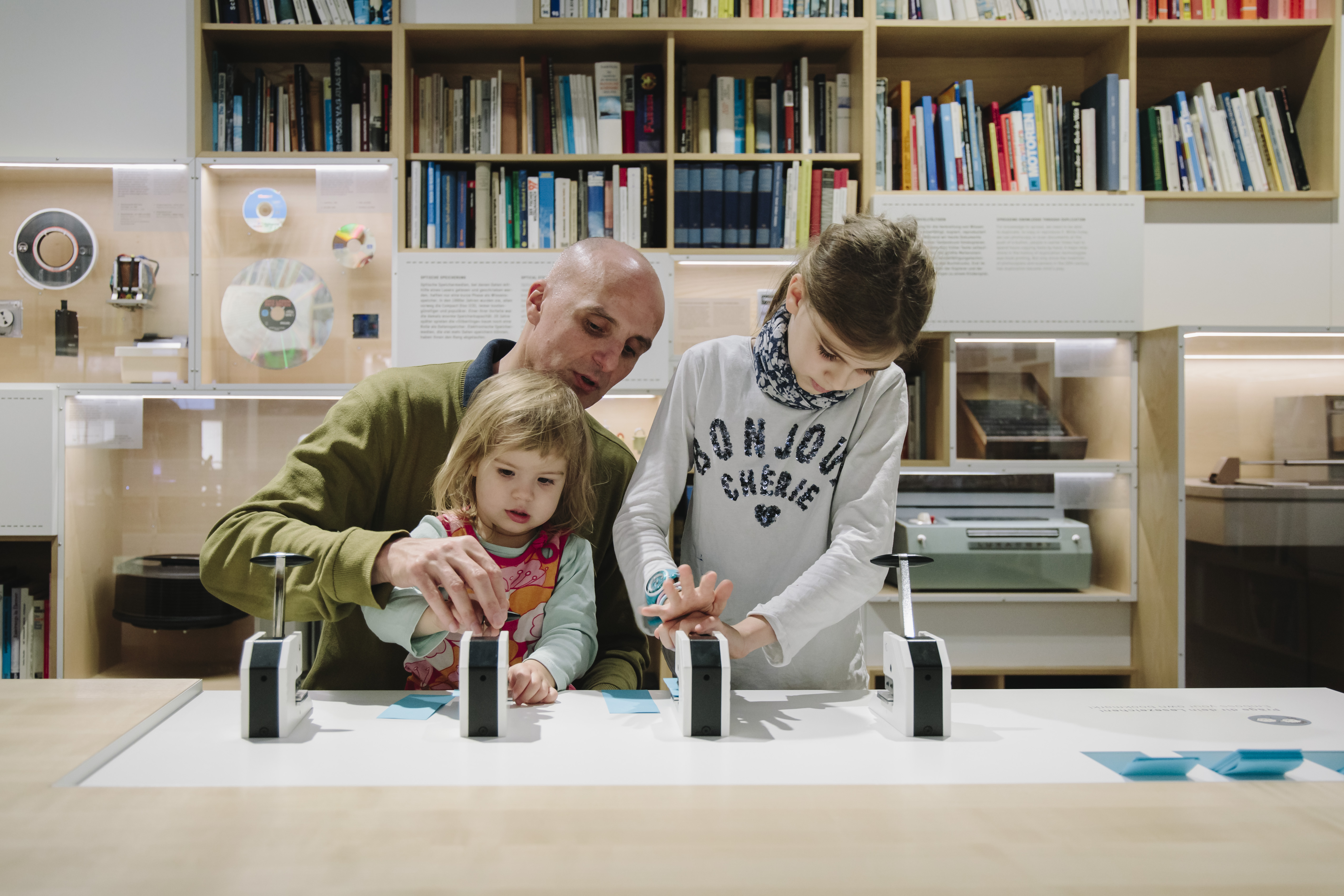 Ein Mann mit zwei kleinen Kinder an einem Mitmach-Tisch in der Netz-Ausstellung