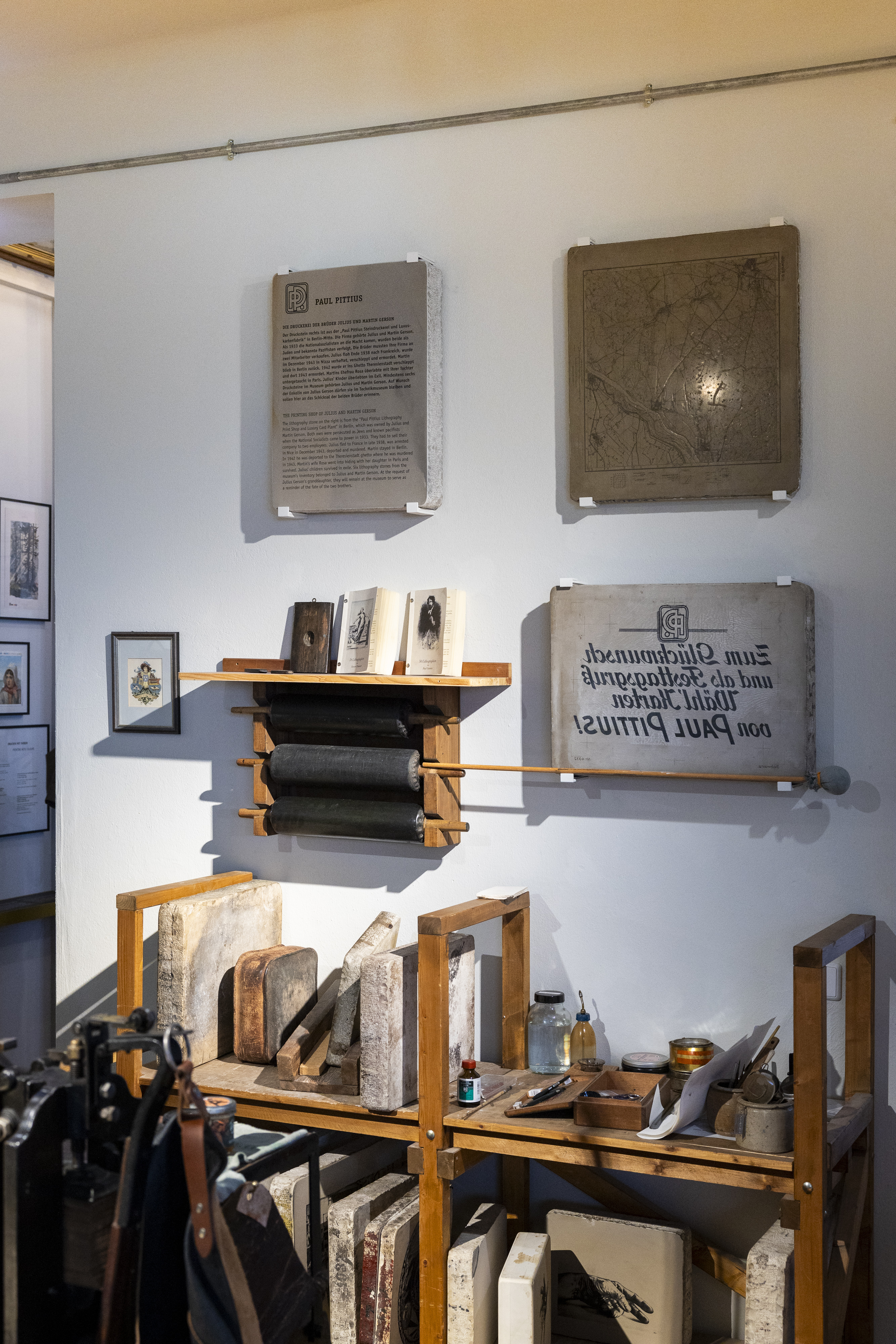 Blick auf eine Ausstellungswand mit Drucksteinen und Geräten für den Steindruck.
