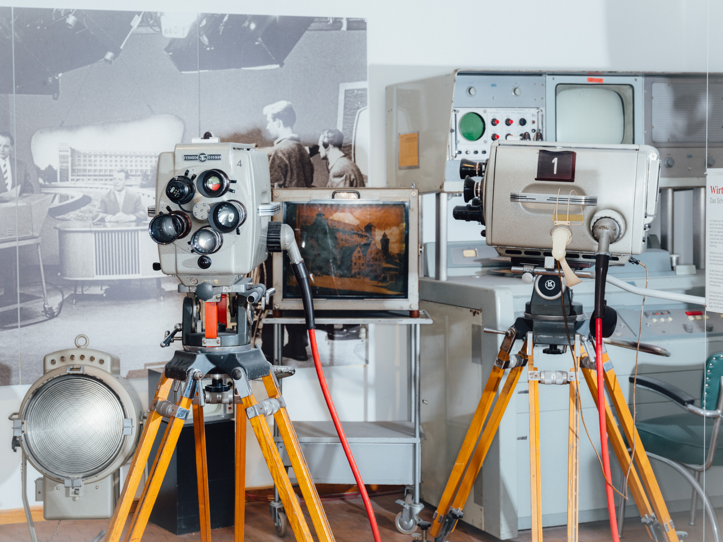 Zwei Fernsehkameras vor einer Wand mit Monitoren.