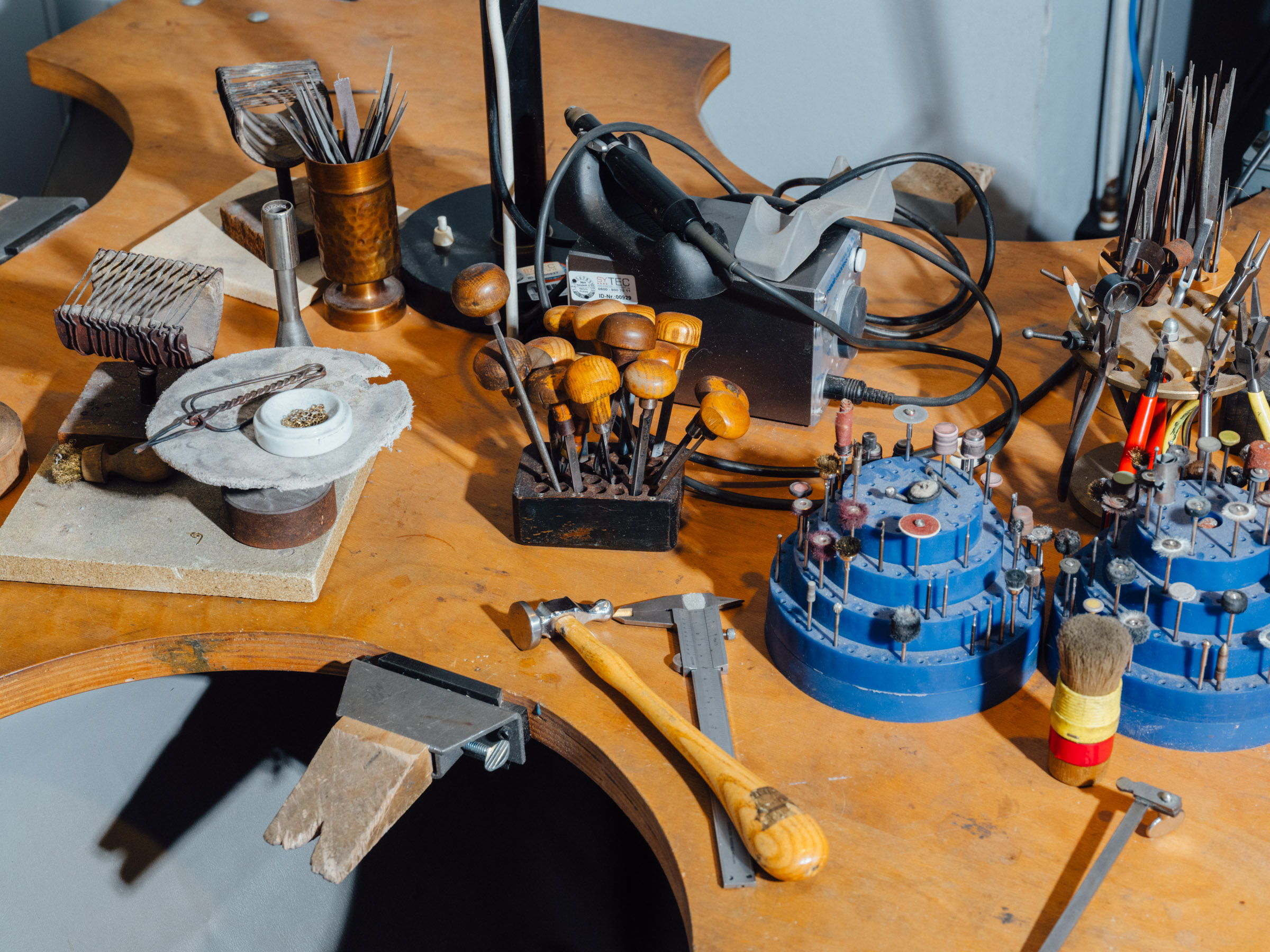 Ein Arbeitstisch mit verschiedenen Werkzeugen zur Metallverarbeitung, darunter Bohrköpfe und Zangen.