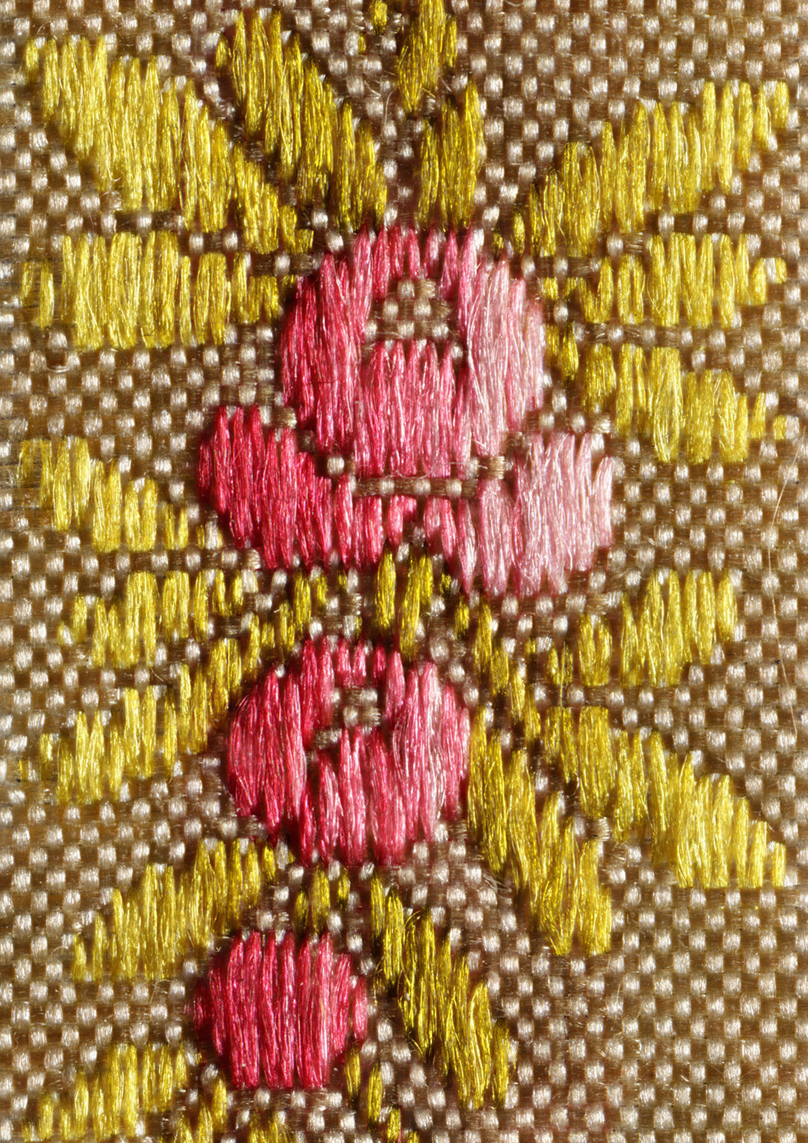 Detailaufnahme eines beigen Gewebes mit rosa schimmernden Blüten und grünen Blättchen.