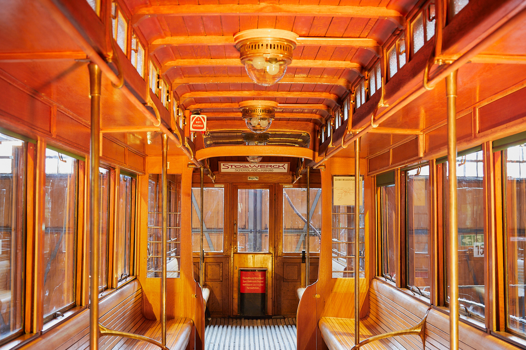 Blick in den Innenraum eines historischen U-Bahnwagens. Die Einrichtung ist aus edlem Holz, die Formen sind geschwungen und elegant, das Design ist dem Jugendstil zuzuordnen.