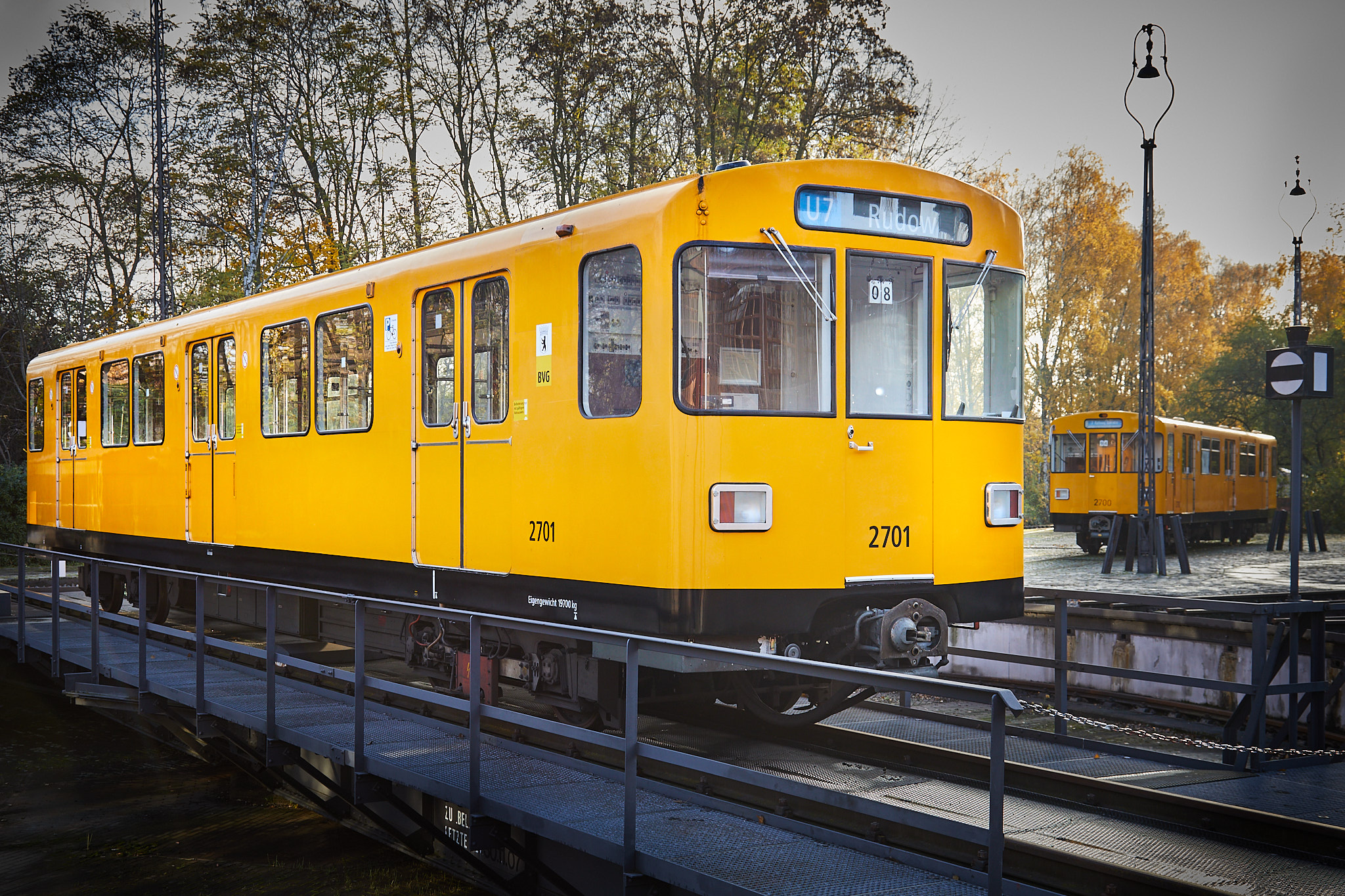 Blick auf einen orangenen U-Bahnwagen, der im Freien auf einer Drehscheibe steht. Die Formen sind rundlich.
