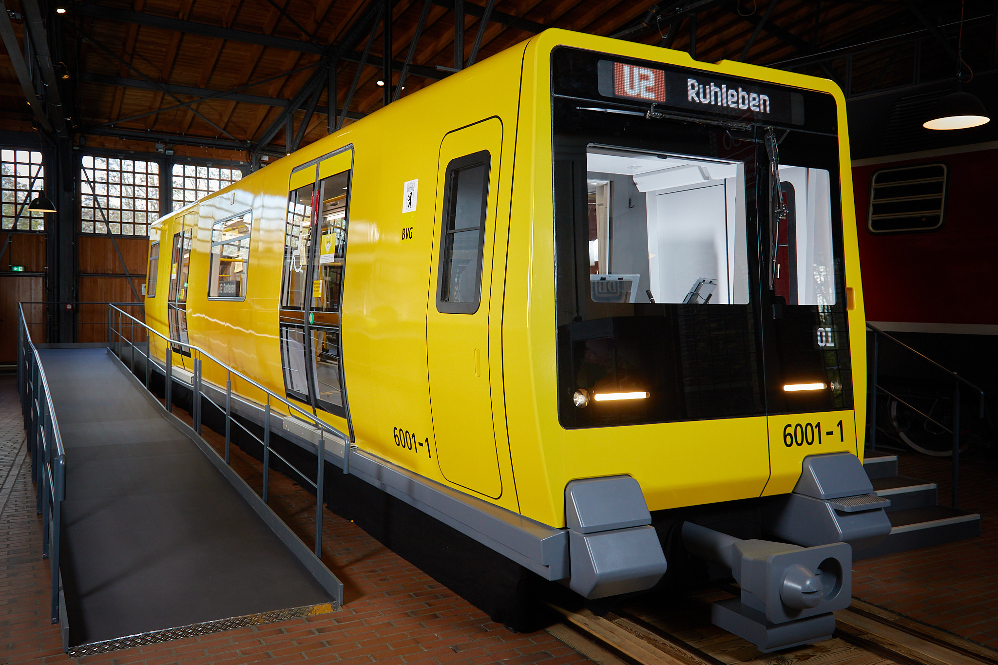 Blick auf das Äußere eines U-Bahnwagens. Der Wagen ist gelb, die Frontpartie schwarz. Der Wagen steht in einem Lokschuppen.
